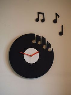 a clock that has musical notes on the side of it and is black with white circles