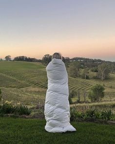 a person wrapped in a blanket sitting on top of a lush green field