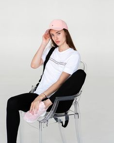 a woman sitting in a chair with a pink hat on her head and black leggings