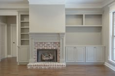 an empty living room with a fireplace and built in bookshelves