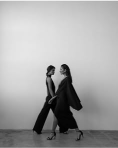 two women are walking together in black and white