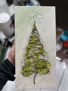 a person holding up a card with a christmas tree on it