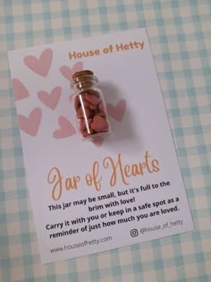 a jar with hearts in it sitting on top of a table next to a card