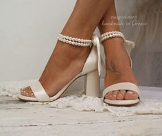 a woman's feet wearing white high heels with pearls on the toes and ankle