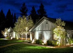 a house that is lit up at night with lights on the front and side of it