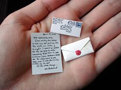 two hands are holding small pieces of paper with words on them and one has a red heart