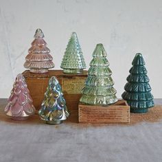 small glass christmas trees sitting on top of a wooden box