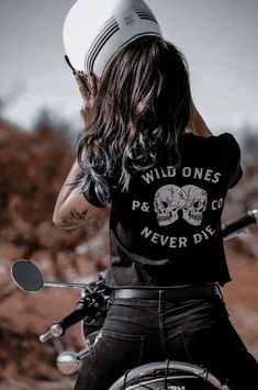 a woman riding on the back of a motorcycle wearing a t - shirt that says wild ones never die