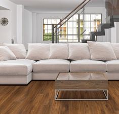 a large white couch sitting in a living room next to a stair case and window