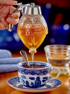 a person pours honey into a tea cup