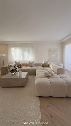 a modern living room with white furniture and wood flooring is pictured in this image