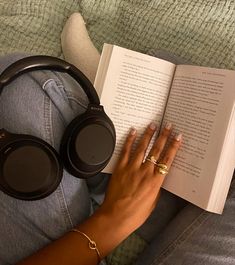 a woman is reading a book and listening to headphones on her lap while laying down