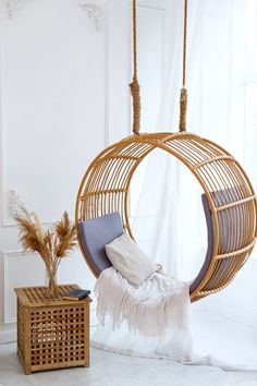 a hammock chair hanging from a rope over a bed in a white room