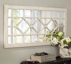 a mirror that is sitting on top of a table next to a vase with flowers