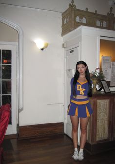 a woman dressed as a cheerleader standing in front of a door with her hands on her hips