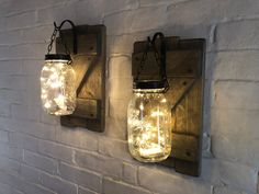 two mason jar lights are hanging on the wall