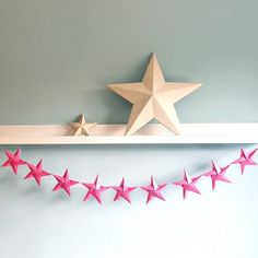 there is a shelf with pink stars on it and a white star hanging from the wall