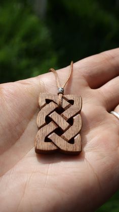 a hand holding a small wooden pendant in it's palm