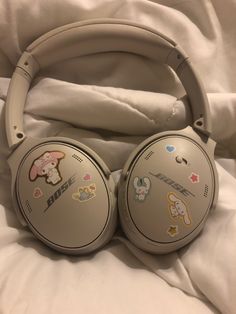 headphones with stickers on them laying on a white bed sheet in a bedroom