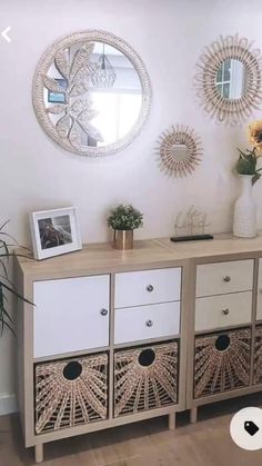 a white and beige sideboard with three baskets on it, two sunflowers in the vase