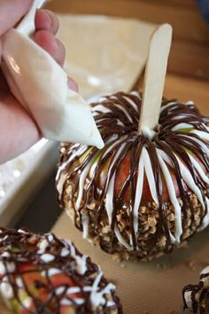 someone is decorating an apple with chocolate and nuts