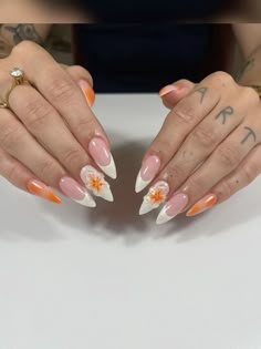 a woman with orange and white nail polish holding her hands over the top of her nails