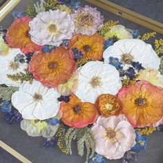 a bunch of flowers that are laying on the ground in front of a mirror and some gold frames