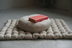 a red book is sitting on top of a round cushion that sits on the floor