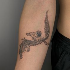 a woman's arm with a tattoo on it that has an image of a winged bird