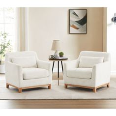 two white chairs sitting on top of a rug in a living room next to a table