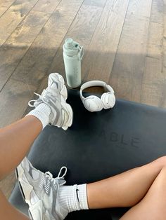 a woman sitting on top of a yoga mat with headphones and a coffee cup