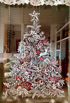 a decorated christmas tree in a window with snowflakes on the top and bottom