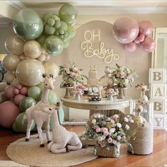 a baby shower with balloons, flowers and giraffe figurines on the floor