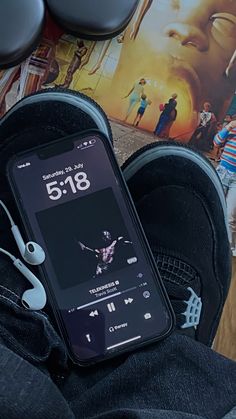 an iphone and headphones laying on top of someone's feet in front of a movie poster