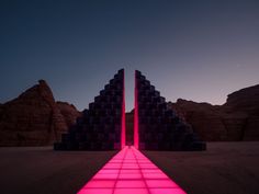 an image of a pink light at the end of a long walkway in front of some mountains