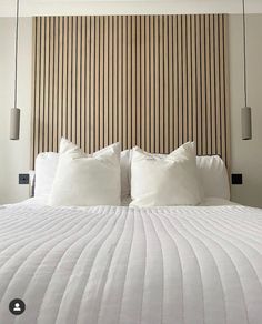 a bed with white pillows and striped headboard