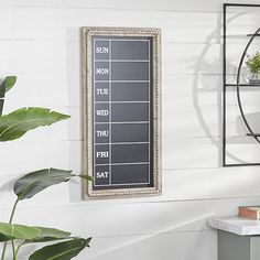 there is a chalkboard on the wall next to a plant and bookshelf