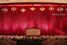 a room with chairs and chandeliers on the wall in front of red backdrop