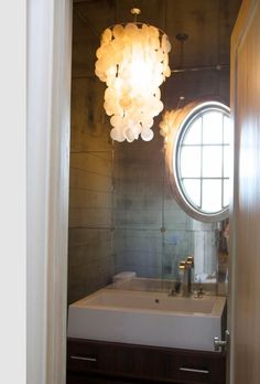 a bathroom with a sink, mirror and round light fixture in the middle of it