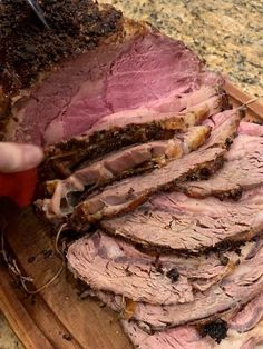 a person cutting up some meat on a wooden board