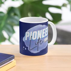 a blue coffee mug with the words phone life on it sitting next to a book