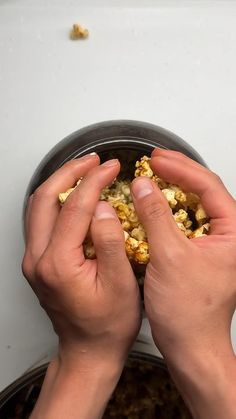 two hands reaching for food in a bowl