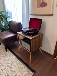 a record player sitting on top of a wooden table next to a brown leather chair