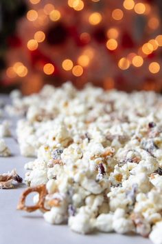 a pile of popcorn sitting on top of a table next to a christmas tree with lights in the background