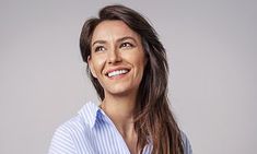 a woman with long brown hair wearing a blue striped shirt and smiling at the camera