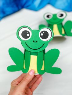 someone is holding up two paper frog puppets