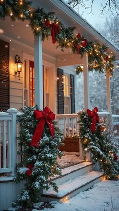 two christmas wreaths on the front porch of a house decorated with red bows and lights