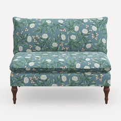 an upholstered couch with blue and white flowers on the back, against a gray background