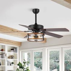 a ceiling fan that is hanging from the ceiling in a room with windows and bookshelves