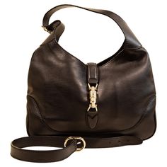 A Gucci Jackie made of black leather with light gold toned hardware. The interior is lined with beige fabric, and next to the major compartment it features three side pockets of which one has a zipper. The bag can be closed with the piston closure. The bag can be worn as a shoulder strap with the short strap (max. 48 cm), or as a crossbody bag with the additional strap (total max. ca. 100 cm). The bag will be delivered with cards, and without the dust bag. The condition of the bag is very good w Gucci Crossbody Bag Vintage, Burberry Crossbody Bag, Gucci Brand, Gucci Outfits, Gucci Tote, Beige Fabric, Vintage Louis Vuitton, Leather Shops, Jack Black